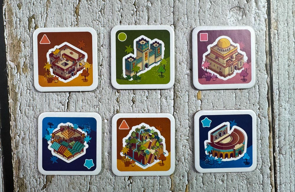 Architects of Amytis board game components and tile layout<br />
Architects of Amytis 3x3 city grid with stacked tiles<br />
Architects of Amytis favor board and pattern cards