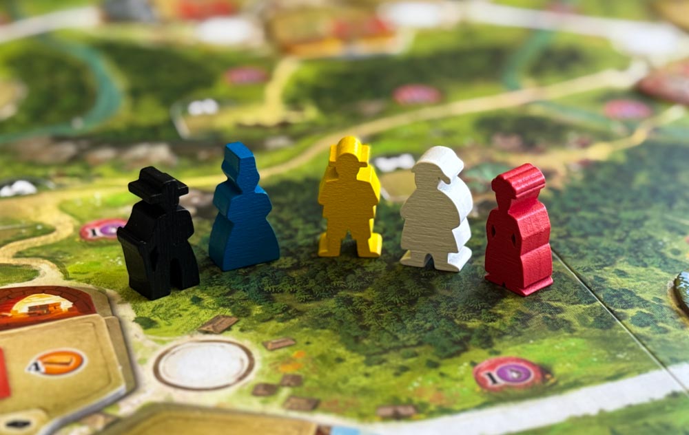 Black Forest board game components showing resource wheels, wooden meeples, and medieval artwork by Uwe Rosenberg