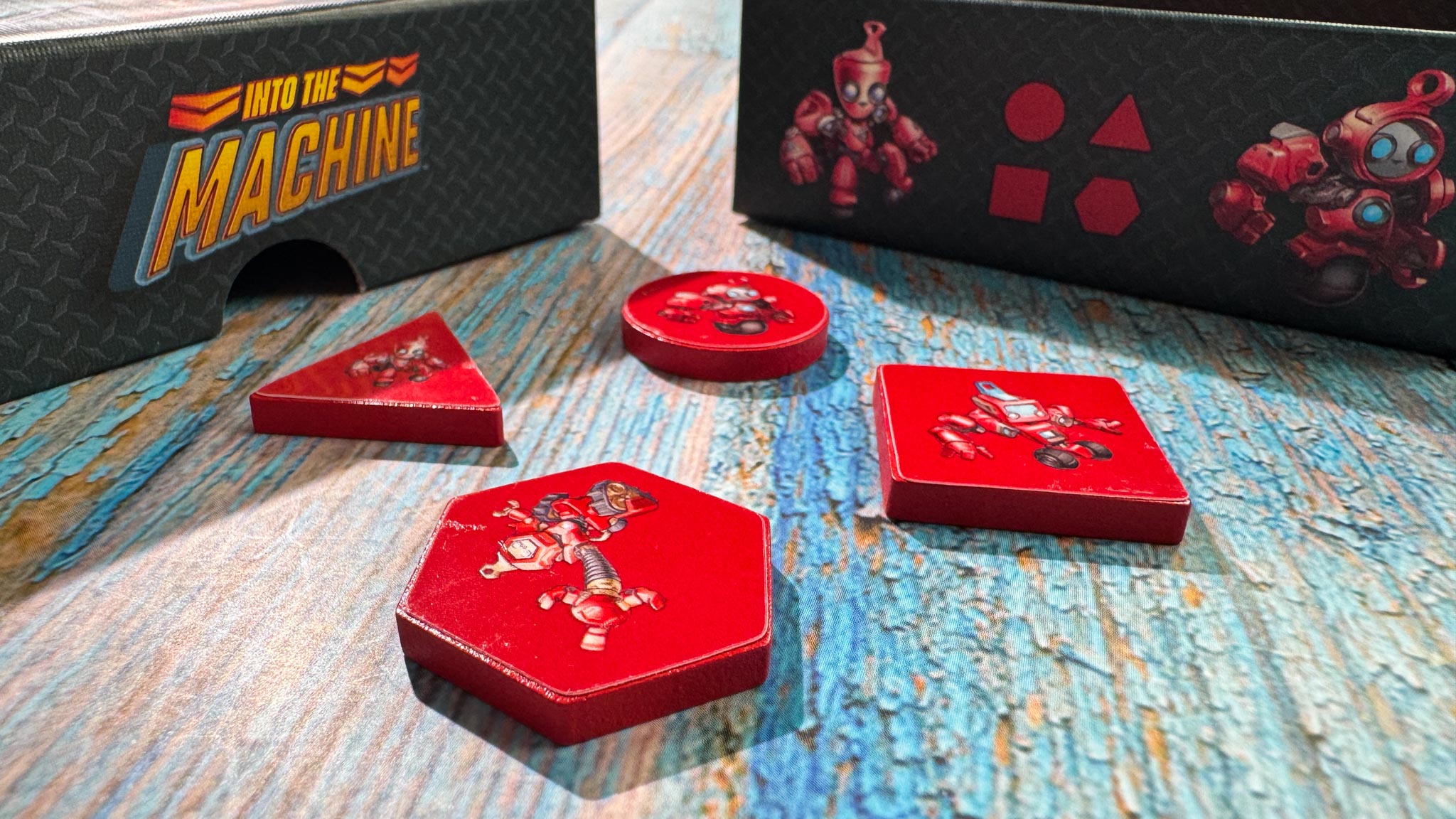 Colorful geometric robot pieces from Into the Machine board game arranged on conveyor belt game board