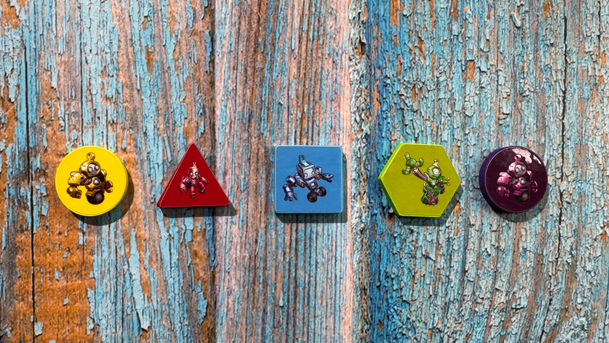 Colorful geometric robot pieces from Into the Machine board game arranged on conveyor belt game board