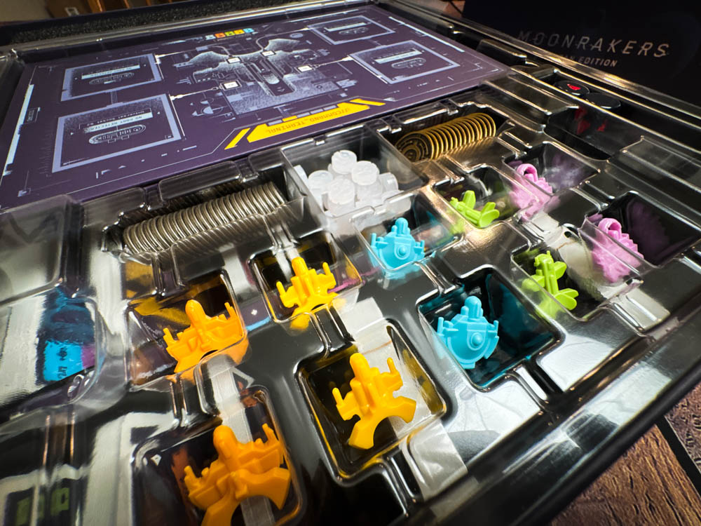 Moonrakers board game review showing deck building cards, contract missions, and player boards with ship upgrades in a space mercenary setting