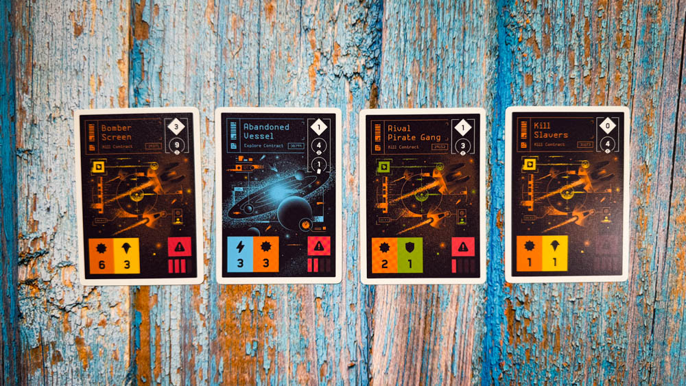 Moonrakers board game review showing deck building cards, contract missions, and player boards with ship upgrades in a space mercenary setting