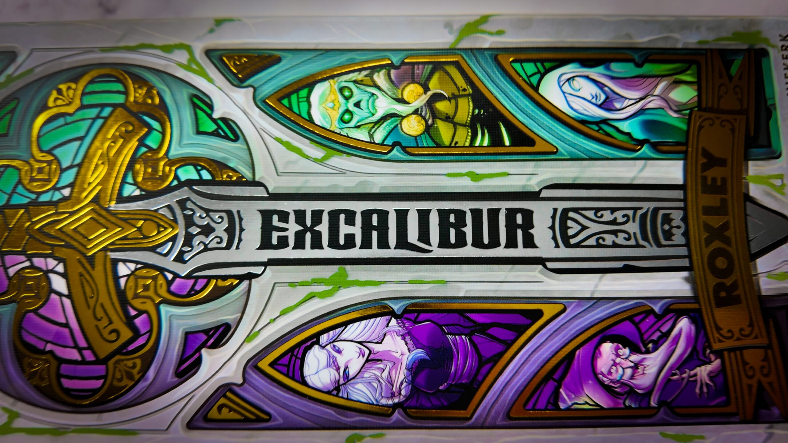 The Excalibur Essentials Edition board game box and components displayed on a wooden table.