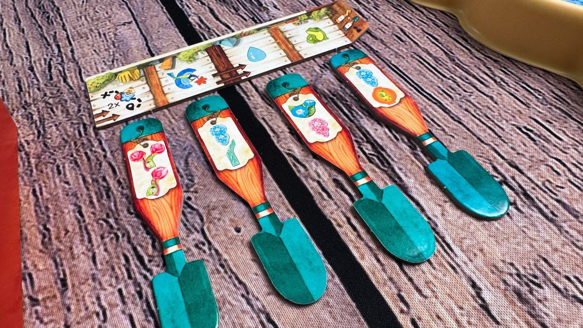 The wooden bee, ladybug, and butterfly tokens on their corresponding flower tiles in Pergola.